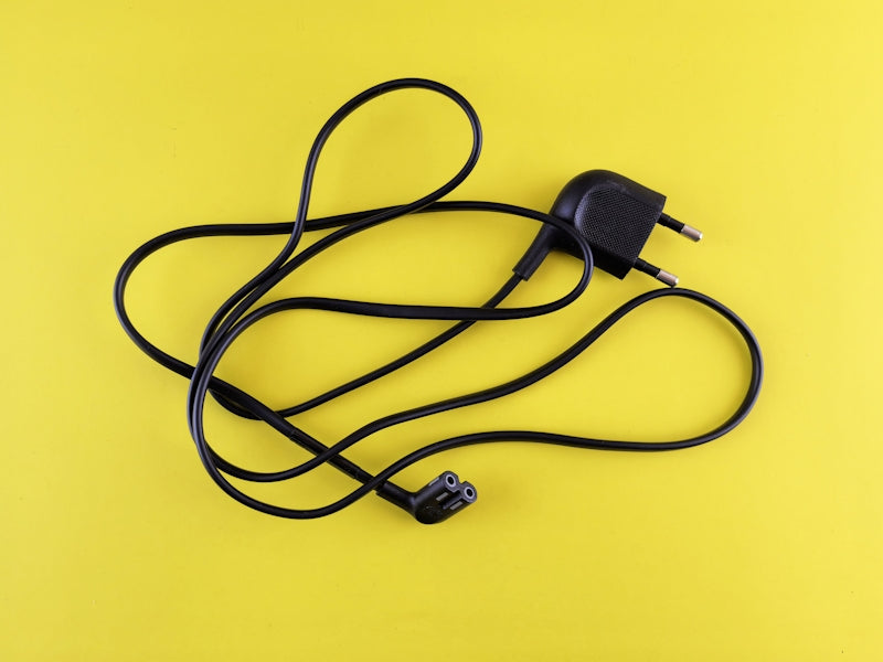 A yellow background with a black cord and a charger