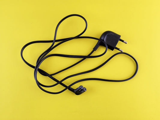 A yellow background with a black cord and a charger