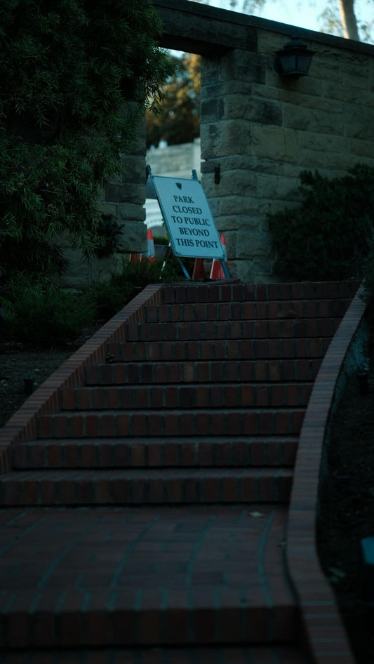 Park closed sign at the bottom of brick stairs.