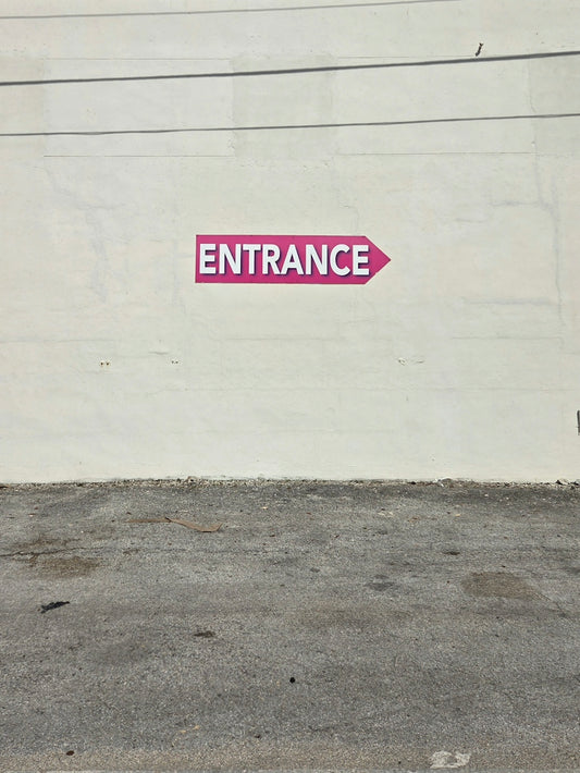 Pink entrance sign on a white wall